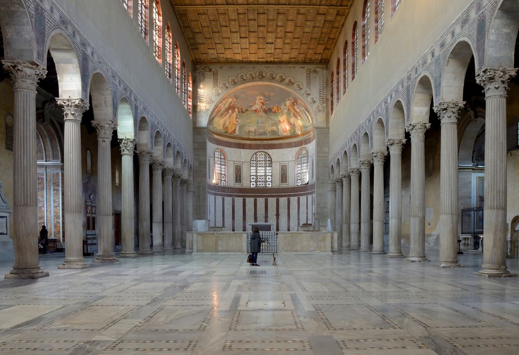 An open nave between two arcades leads to a screened recess with a curved wall, three windows and a painted semi-dome.