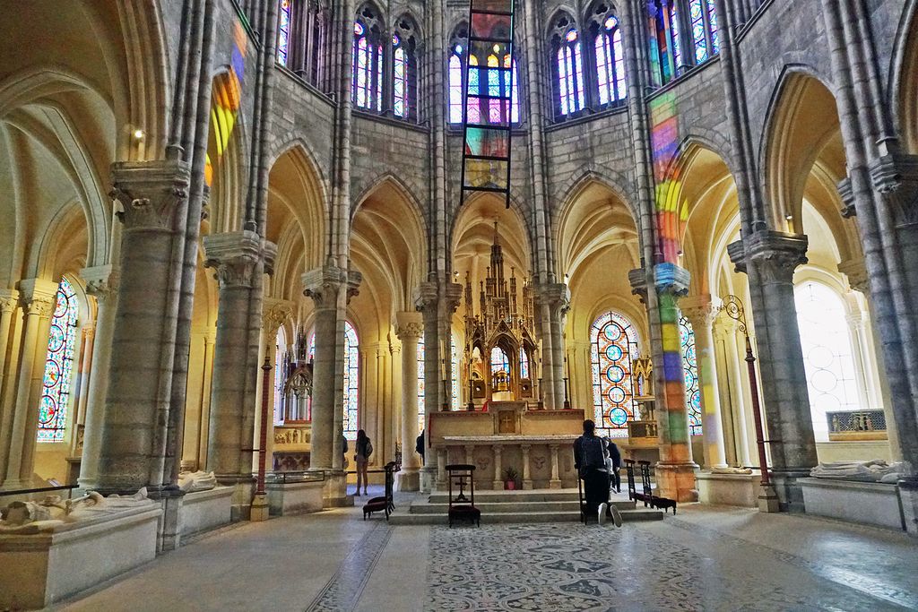 A freestanding altar stands within a ring of tall columns and pointed arches, with passages and stained-glass chapels behind.