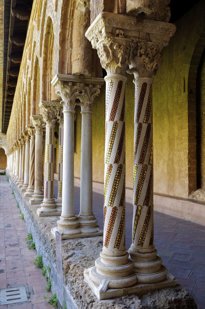 Pairs of marble columns, some with diagonal mosaic bands, support carved double capitals above a low stone wall.