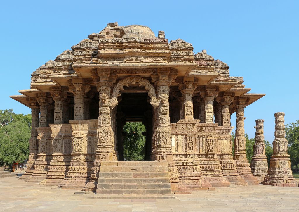 Broad steps lead through an ornate opening into a carved pillared hall with low enclosure walls and deep eaves.