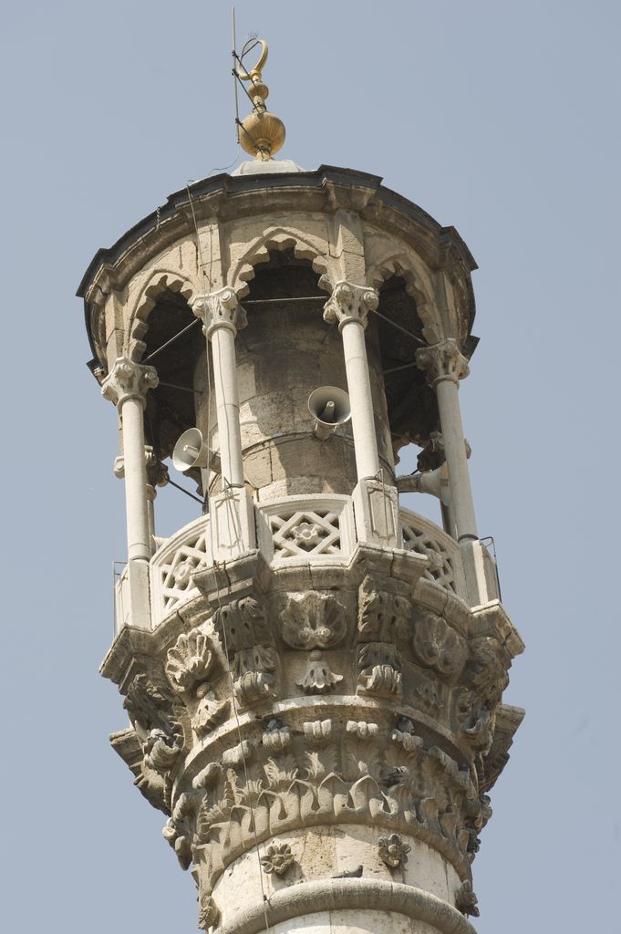 Horn loudspeakers and cables sit between the slender columns of an ornate roofed minaret balcony.