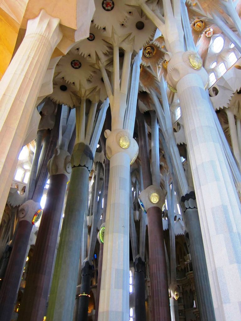 Tall faceted columns divide above rounded nodes into angled supports beneath complex vault surfaces.