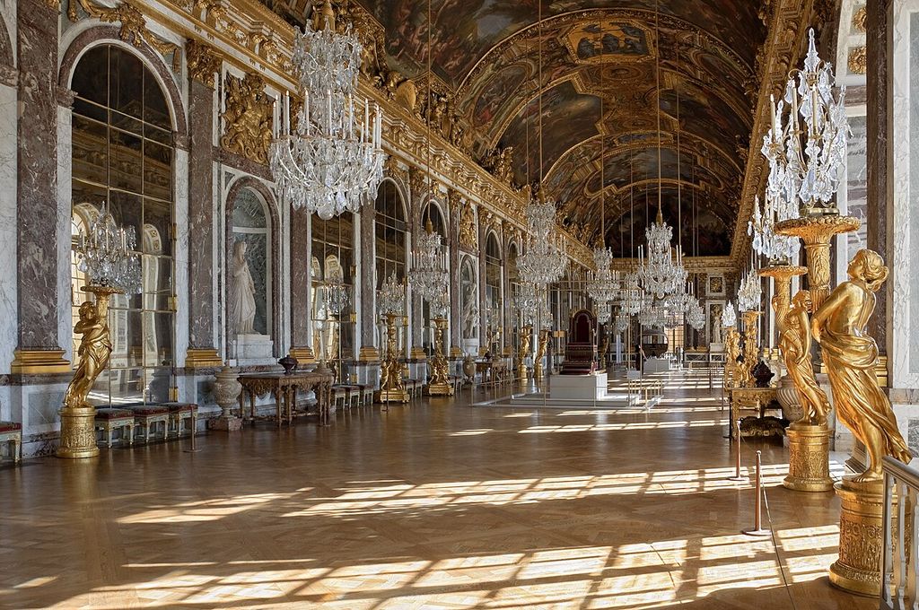 Sunlight falls across parquet beneath chandeliers and a painted vault, beside a long wall of mirrored arches at Versailles.