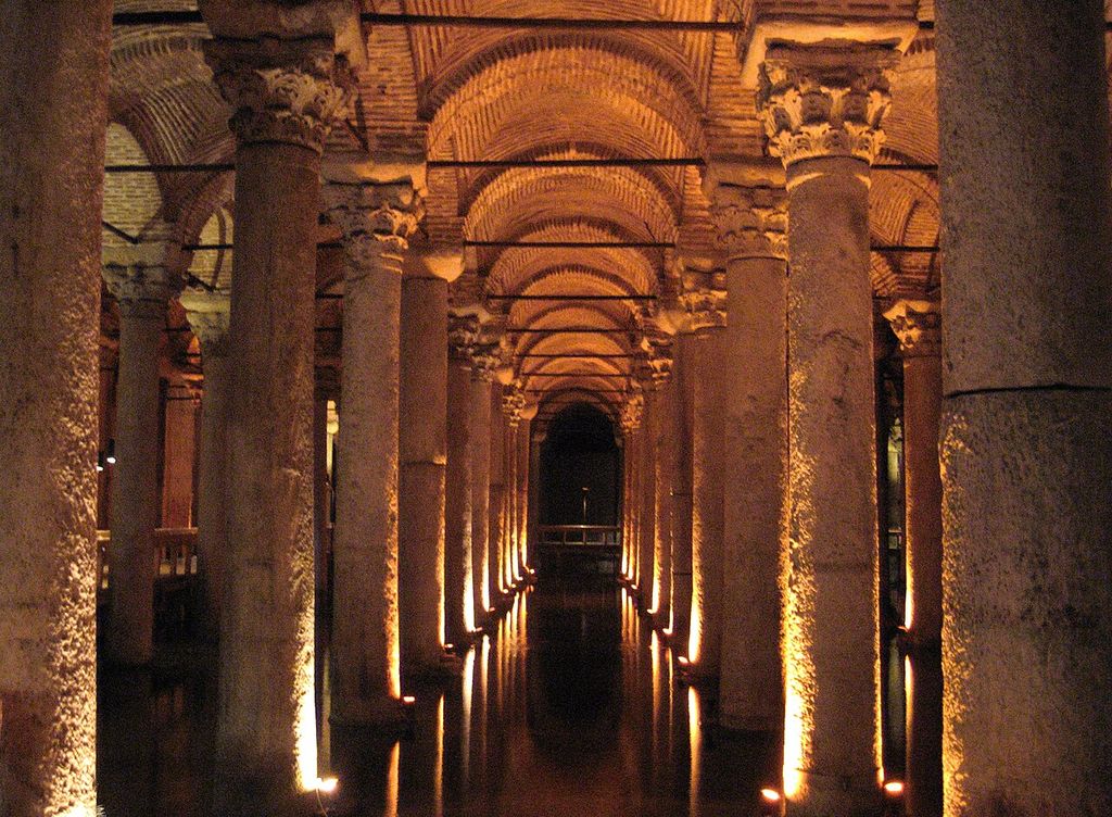 Stone columns supporting brick vaults recede through the Basilica Cistern above dark water and reflected lights.