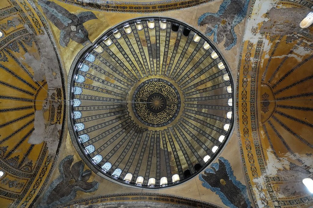 A window-lined dome rises between four curved triangular pendentives bearing seraphim, with calligraphy at its centre.