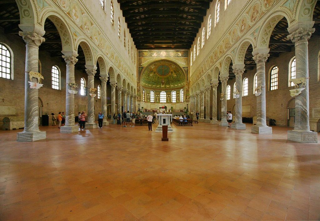 Two rows of columns and arches flank the long nave of Sant’Apollinare in Classe, with a mosaic apse ahead.