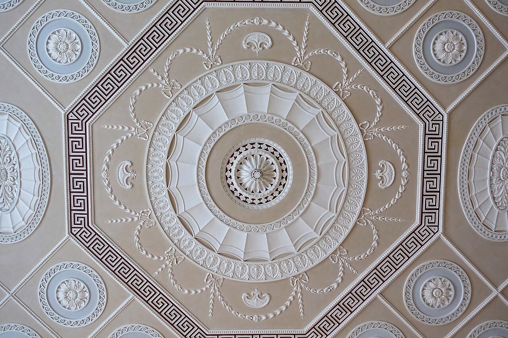 Pale rosettes, foliage and geometric meander bands arranged around a circular ceiling centre.