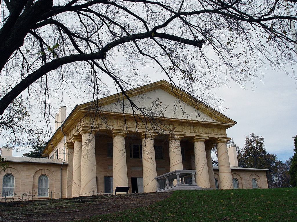 Large columns with painted veining support a broad pediment beneath overhanging bare branches.
