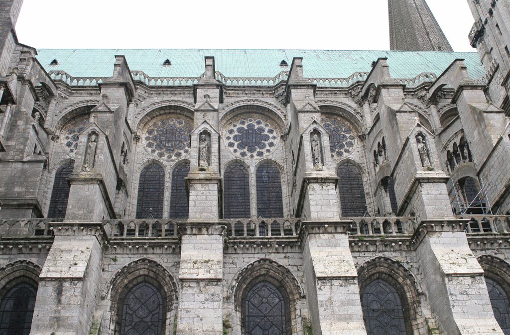 Rows of stone buttresses and tall traceried windows along the north side of Chartres Cathedral.