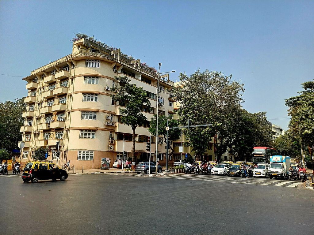 Rounded balconies and rows of windows on the Moonlight apartment building beside a busy Mumbai street.