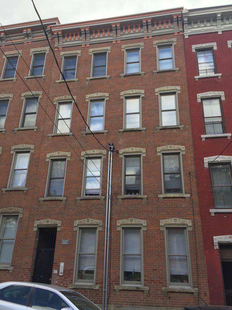 Tall brick façades have closely spaced vertical windows with projecting decorative heads beneath bracketed cornices.