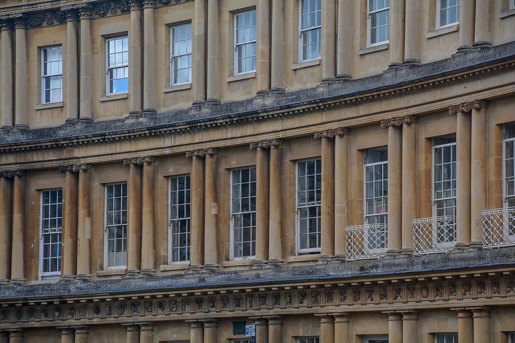 Stacked rows of columns and sash windows following a curved stone terrace, divided by entablatures and a decorated frieze.