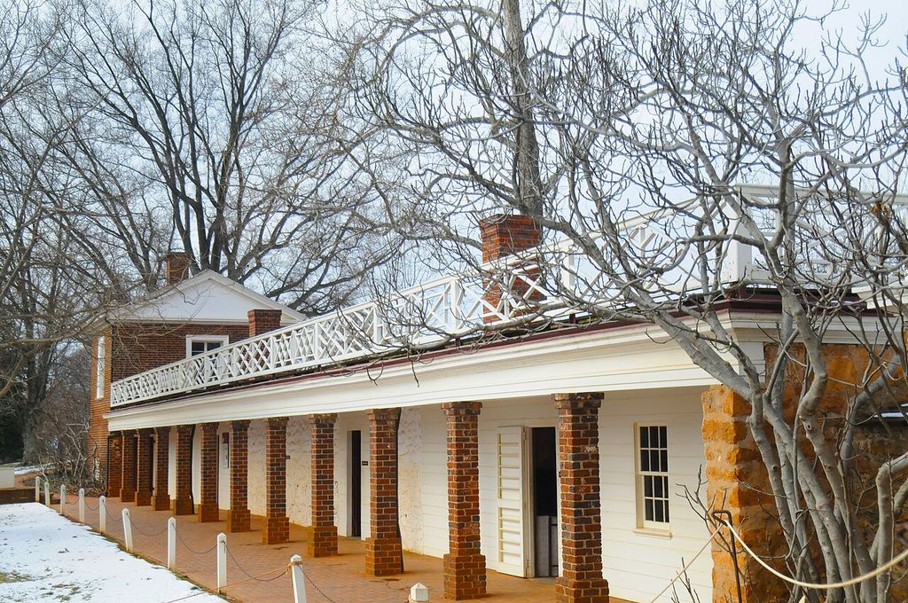Brick piers and doorways beneath a long balustraded terrace at Monticello, with snow along the path.