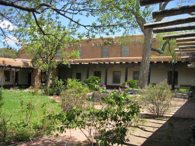A garden of trees and shrubs is enclosed by earth-coloured office walls and a covered timber portal.