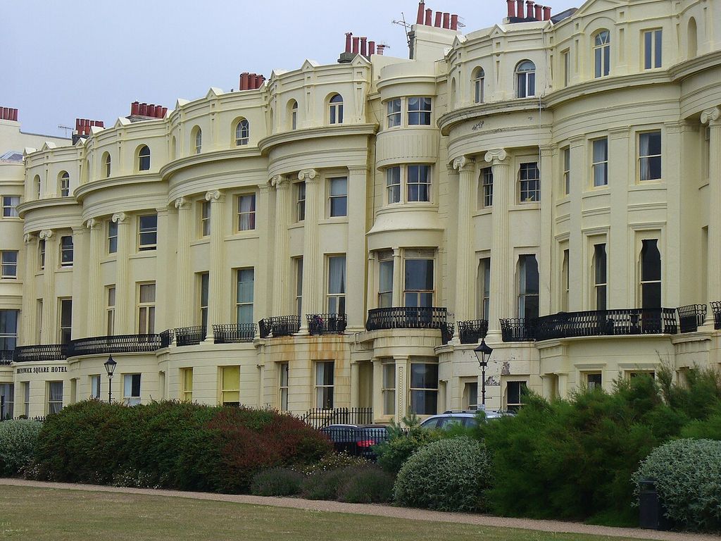 Pale curved façades combine sash windows, tall Ionic members and dark iron balconies.