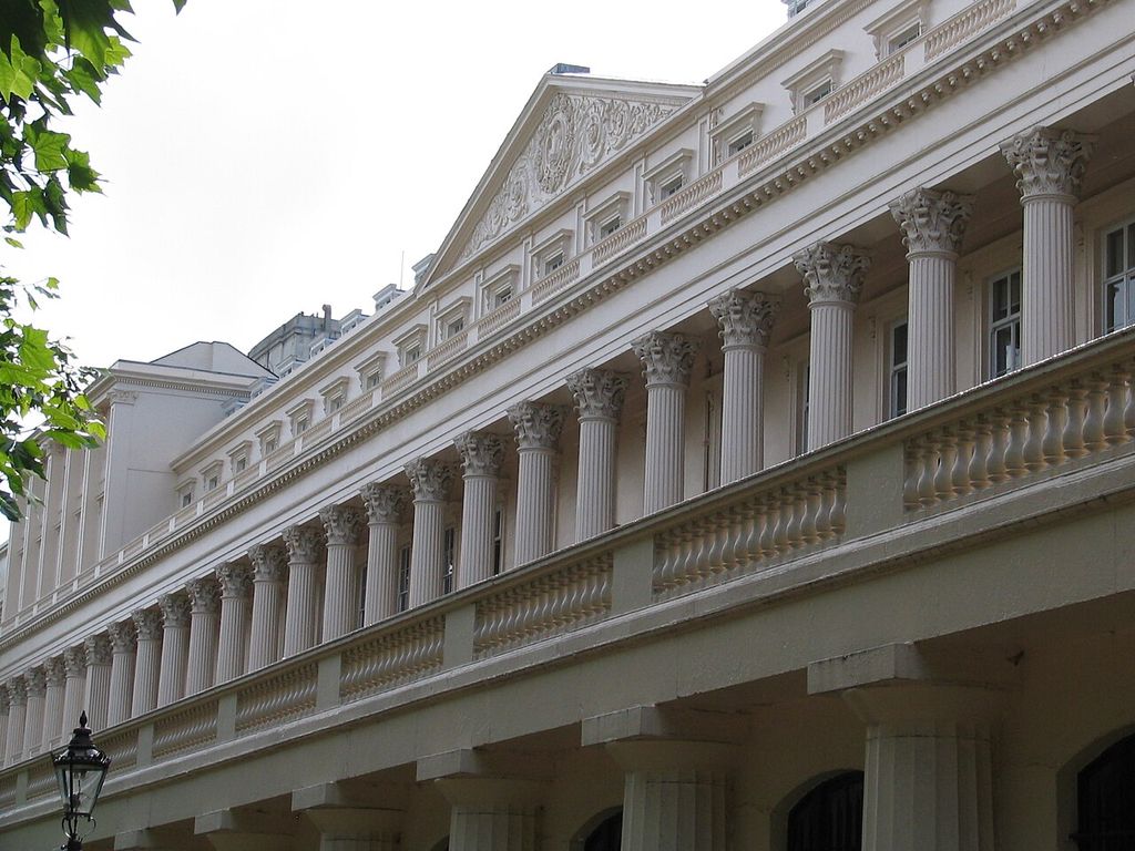 A giant Corinthian colonnade and balustrade run beneath repeated windows and a pediment.