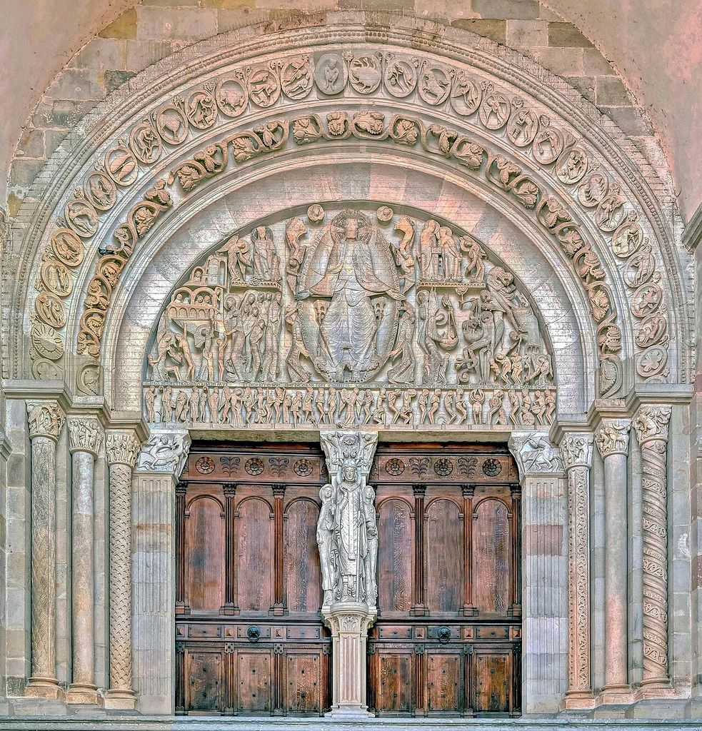 A semicircular Last Judgment relief sits above a double doorway, surrounded by carved archivolts, columns and capitals.