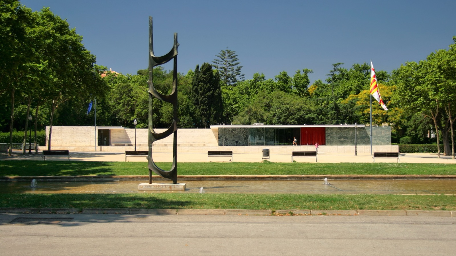 Reconstructed Barcelona Pavilion across a pool, showing low plinth, long horizontal roof, glass and marble walls and sculpture.