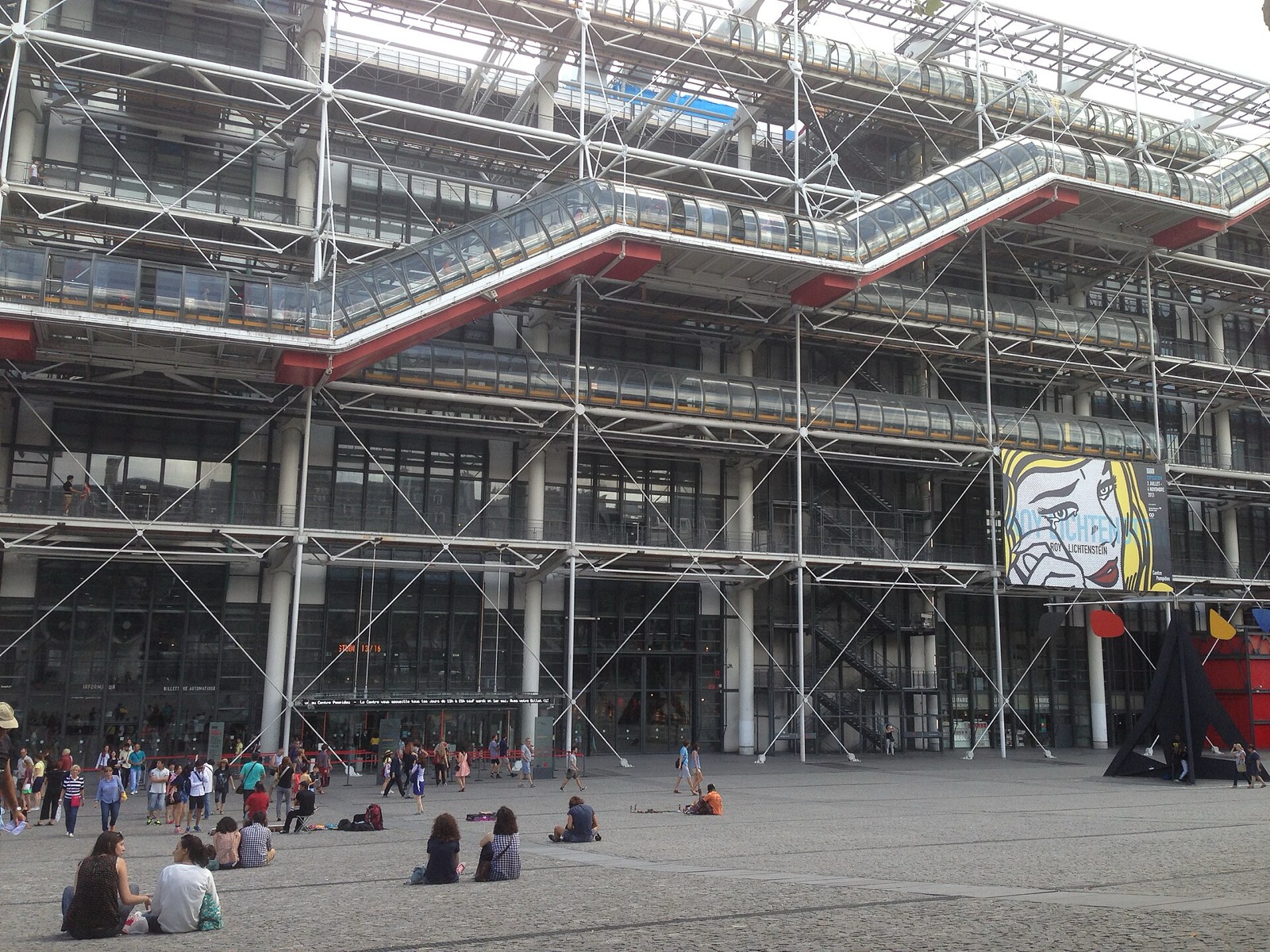 Centre Pompidou façade and piazza with exposed steel bays, diagonal bracing, external escalator tubes and people.
