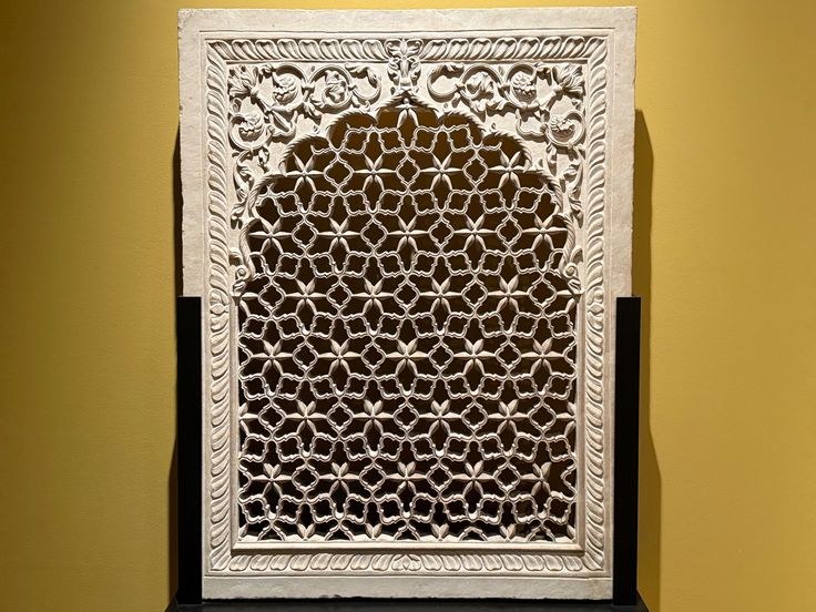 Carved sandstone jali panel with a dense geometric lattice and visibly deep perforations.