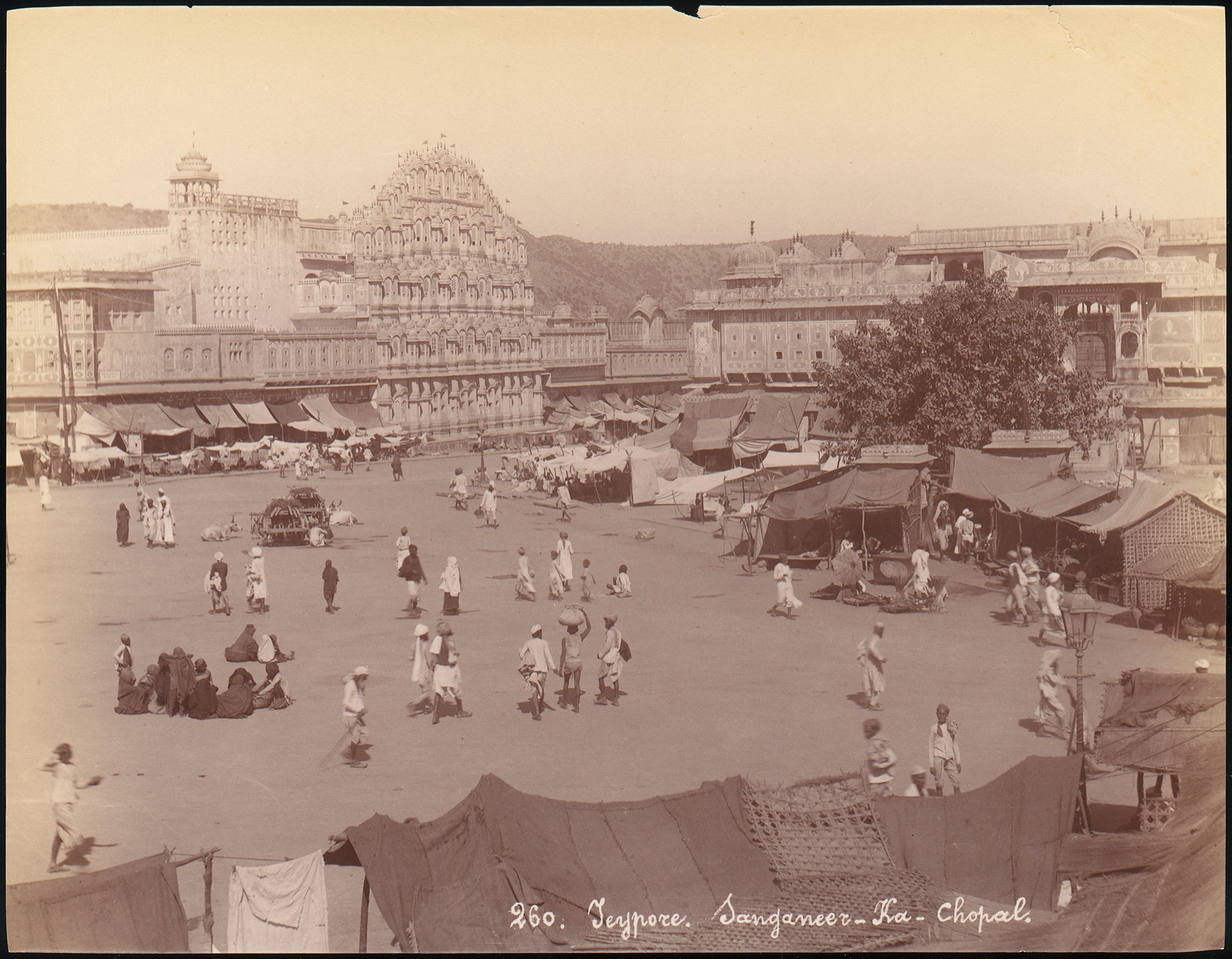 Nineteenth-century sepia photograph of Sanganeer-ka-Chopal near Jaipur, with shop tents, walkers and ornate built façades.