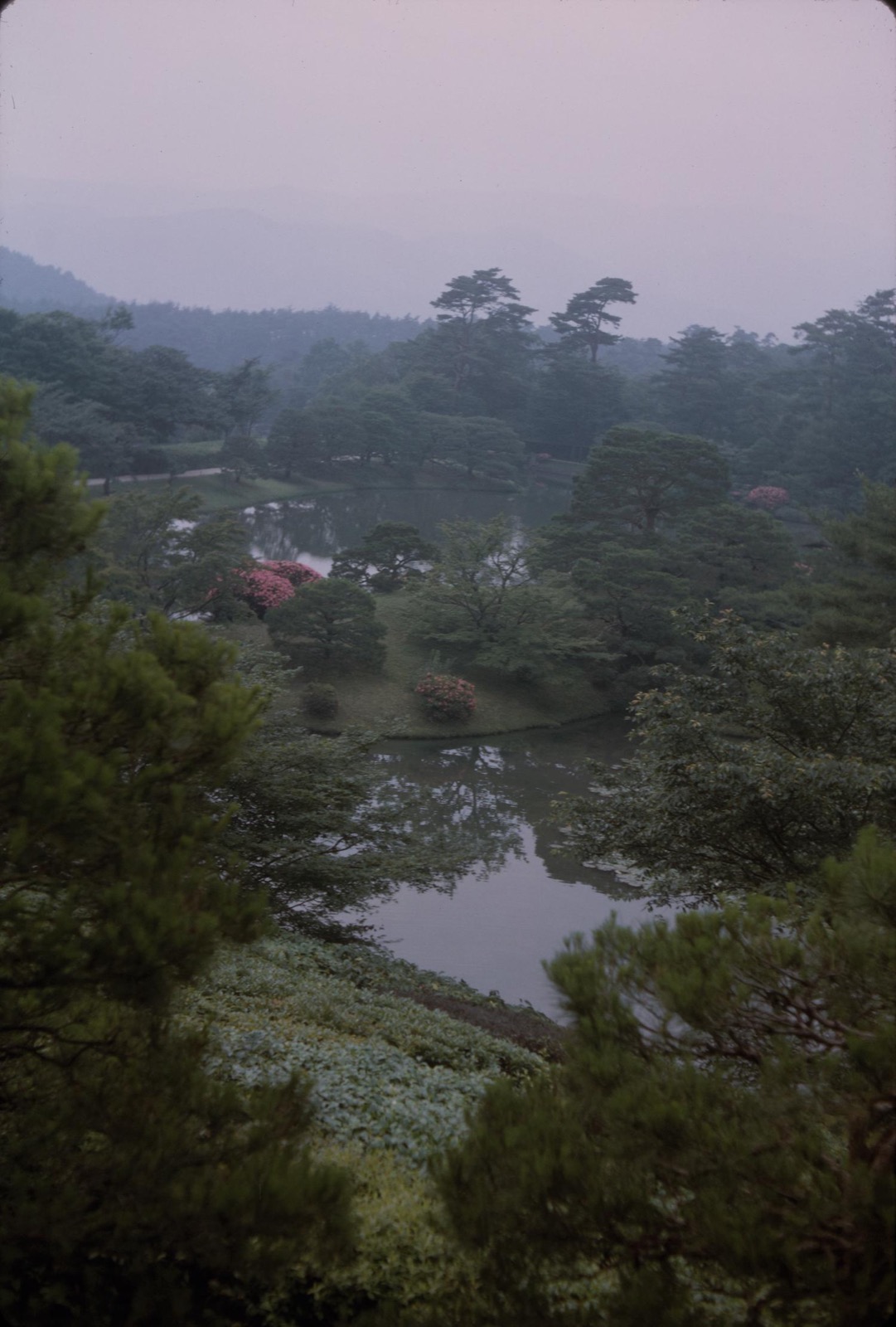 Archival Shugakuin garden view across a planted landscape and water toward trees and distant hills.