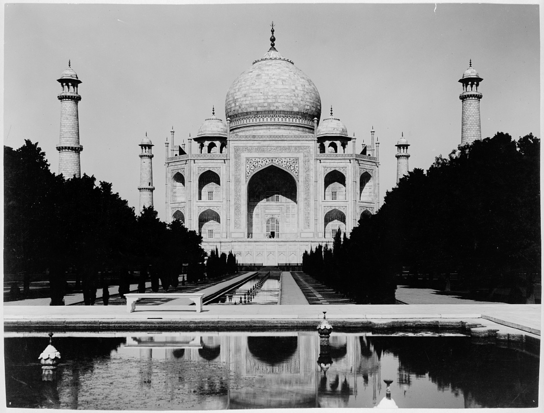 Circa-1920 photograph approaching the Taj Mahal along reflecting water and central garden path.