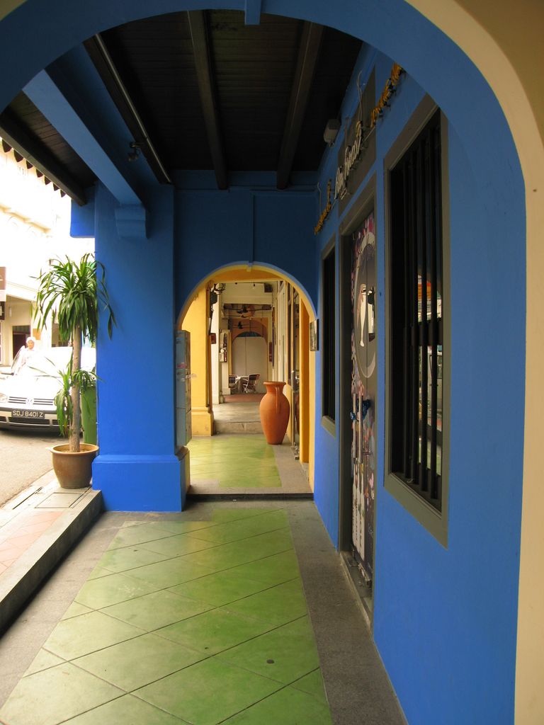 A covered pedestrian passage runs through repeated arches alongside shopfronts and the street.