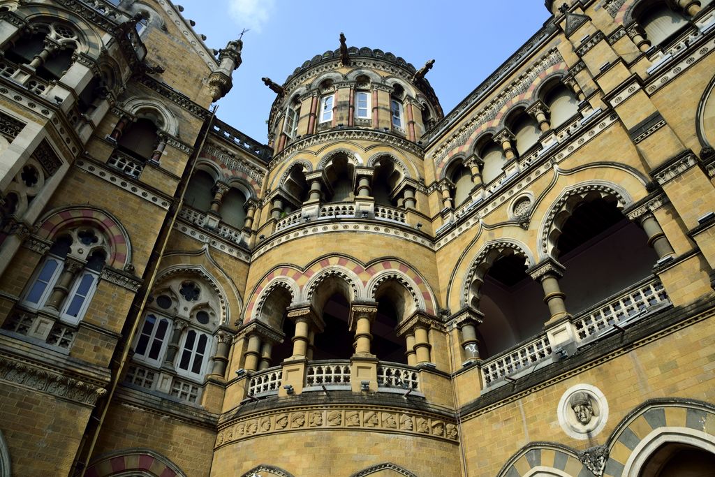 Carved columns and reliefs frame stacked arcades and a curved bay in patterned stonework.