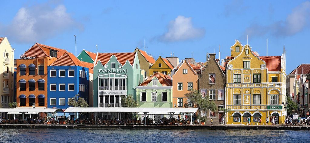 Colourful narrow commercial fronts with varied gables, balconies and arcades stand beside the water.