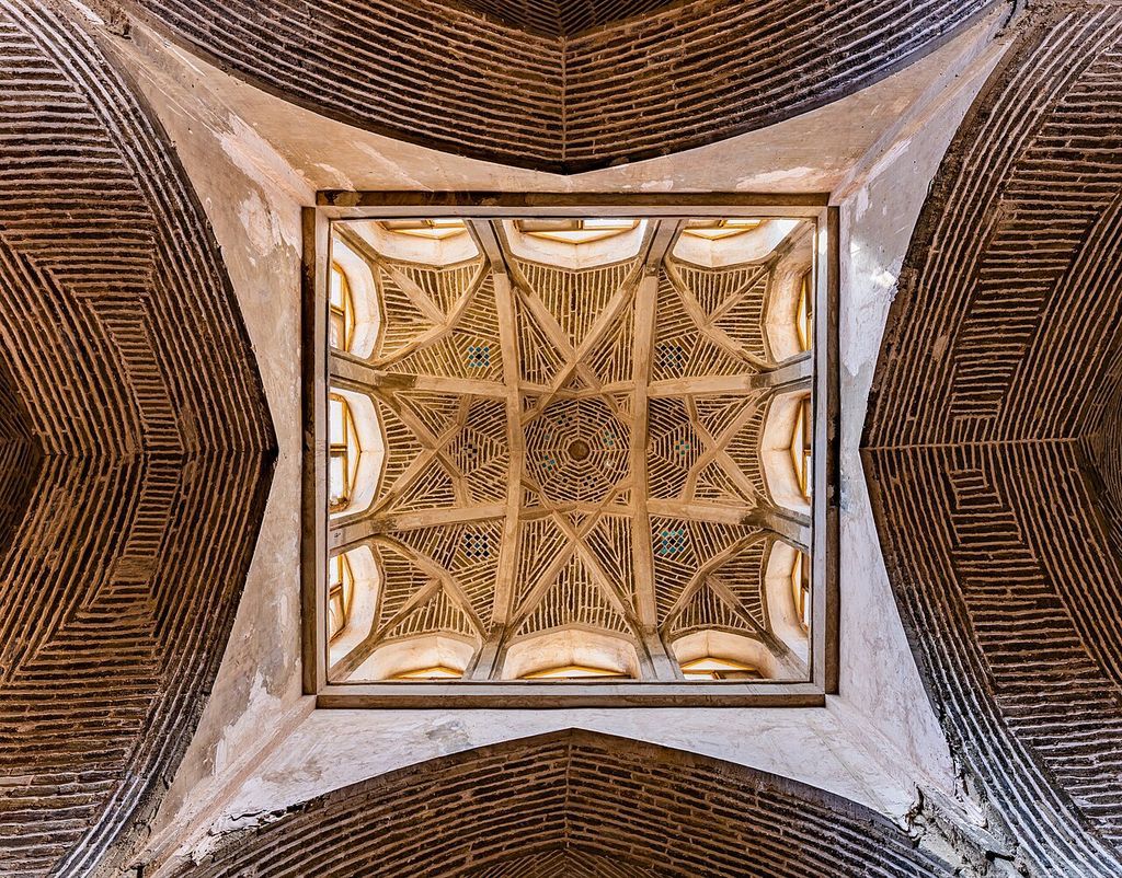 An upward view shows a square brick vault crossed by geometric ribs and surrounded by curved patterned brick surfaces.