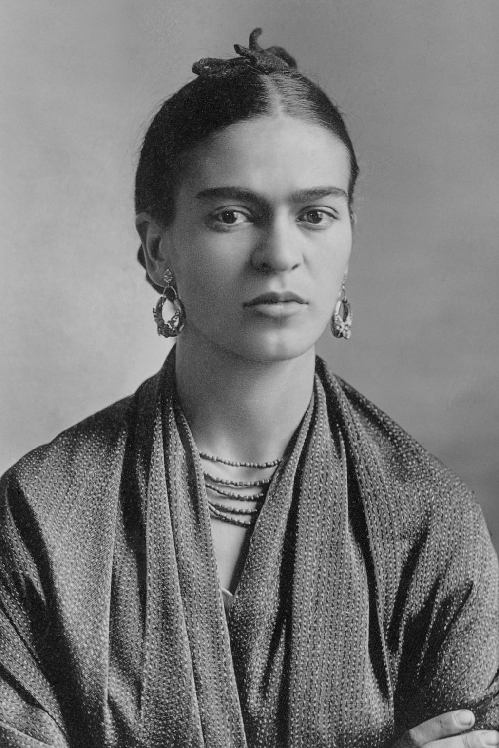 Black-and-white portrait of Frida Kahlo seated and looking toward the camera in 1932.