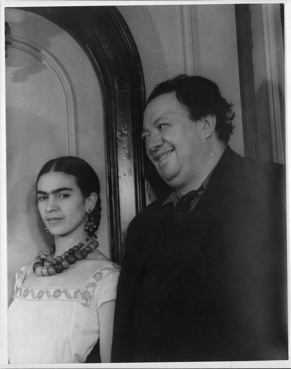 Black-and-white studio portrait of Frida Kahlo seated beside Diego Rivera in 1932.