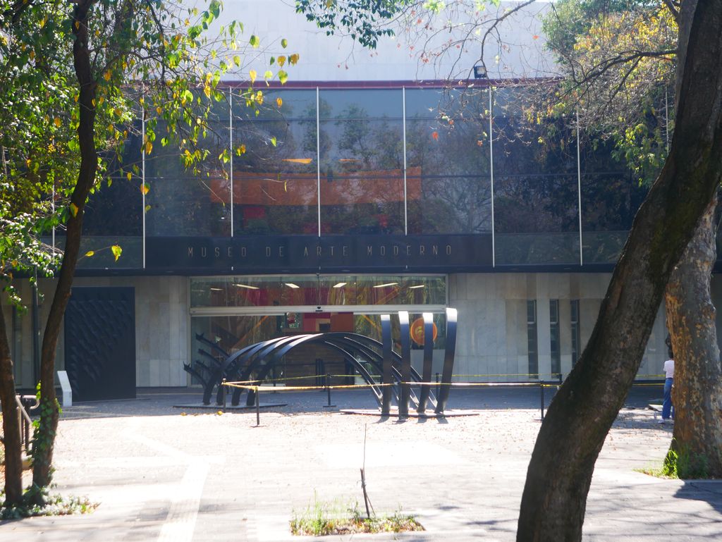 Curved white facade of the Museo de Arte Moderno in Chapultepec, with a dark abstract sculpture in the foreground.