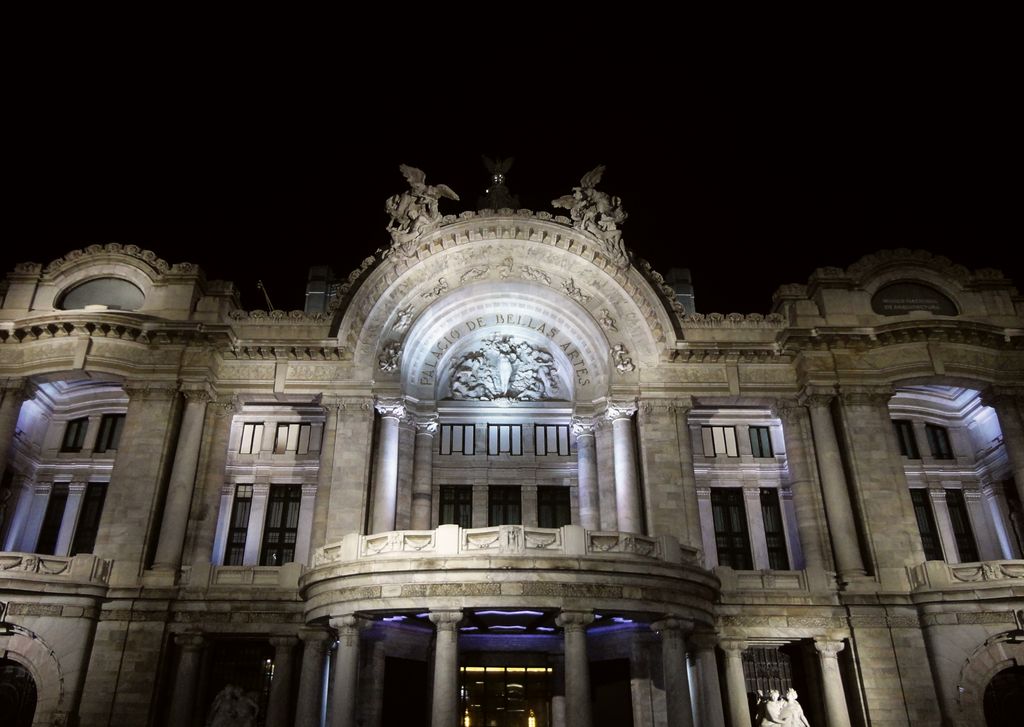 Illuminated white-marble facade and domed roof of the Palacio de Bellas Artes at night.