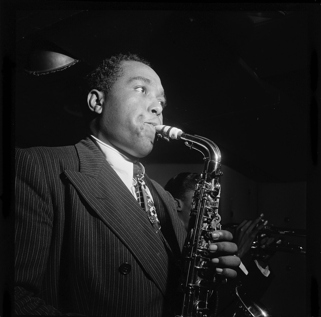 Charlie Parker holding a saxophone to his mouth on stage.