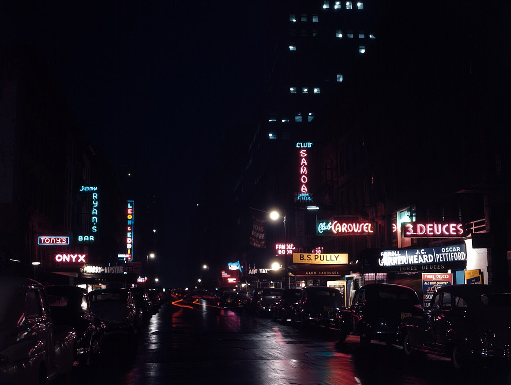Neon signs for jazz clubs above a dark New York street.