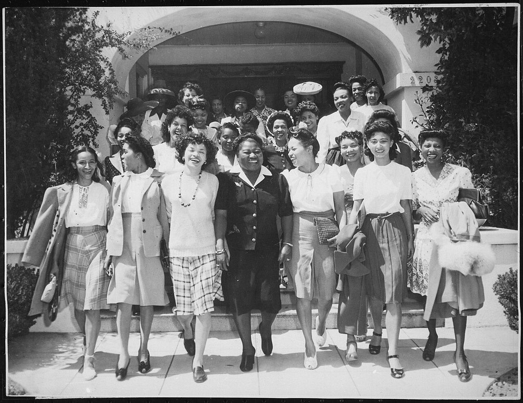 Hattie McDaniel standing at the front centre of a group of entertainers on outdoor steps.