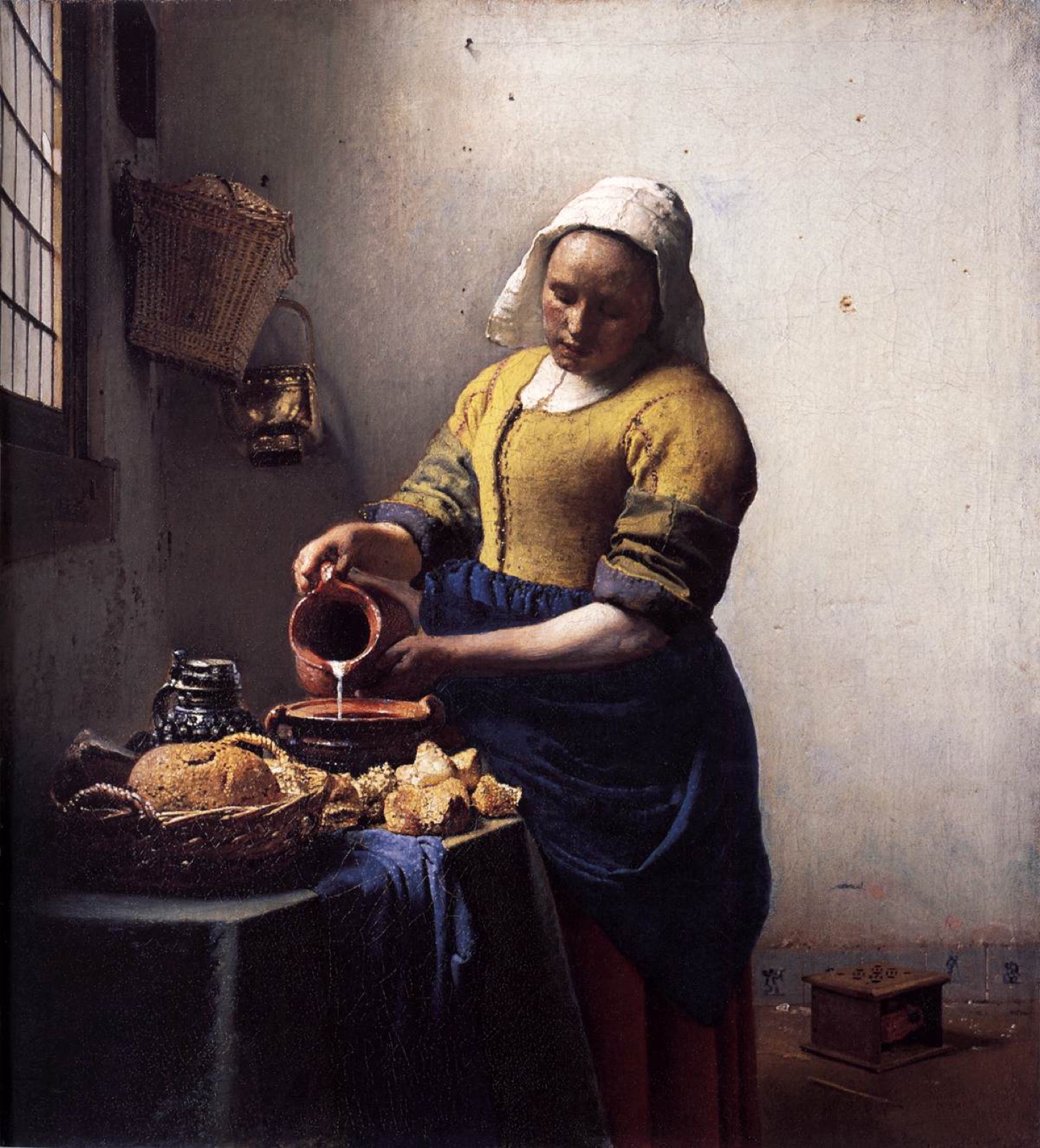 A maid pours milk beside bread and kitchen vessels in a sunlit room