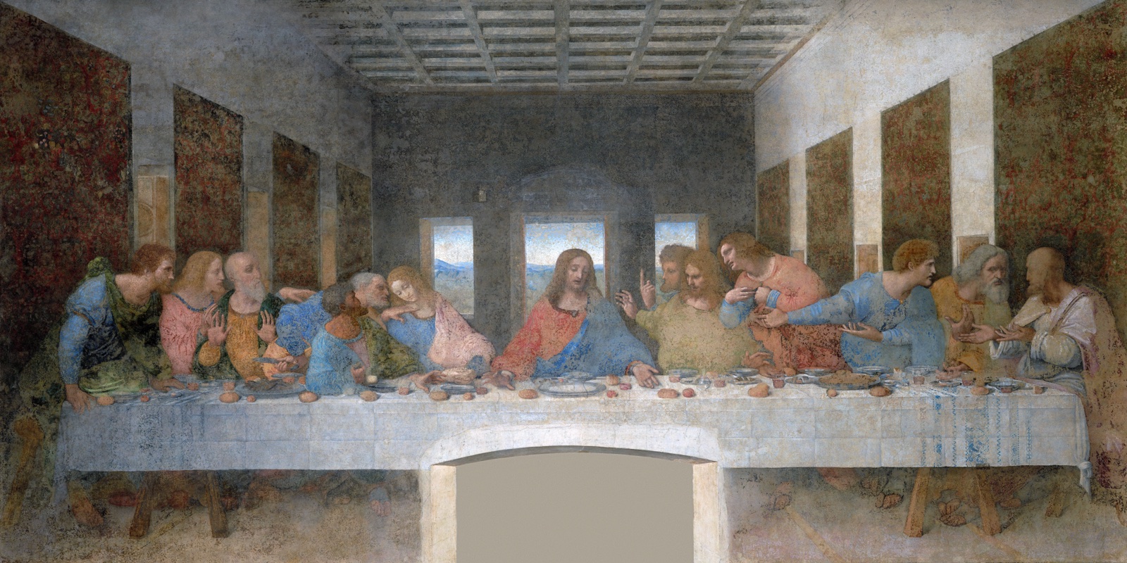 Jesus sits at the centre of a long table as the twelve apostles react around him