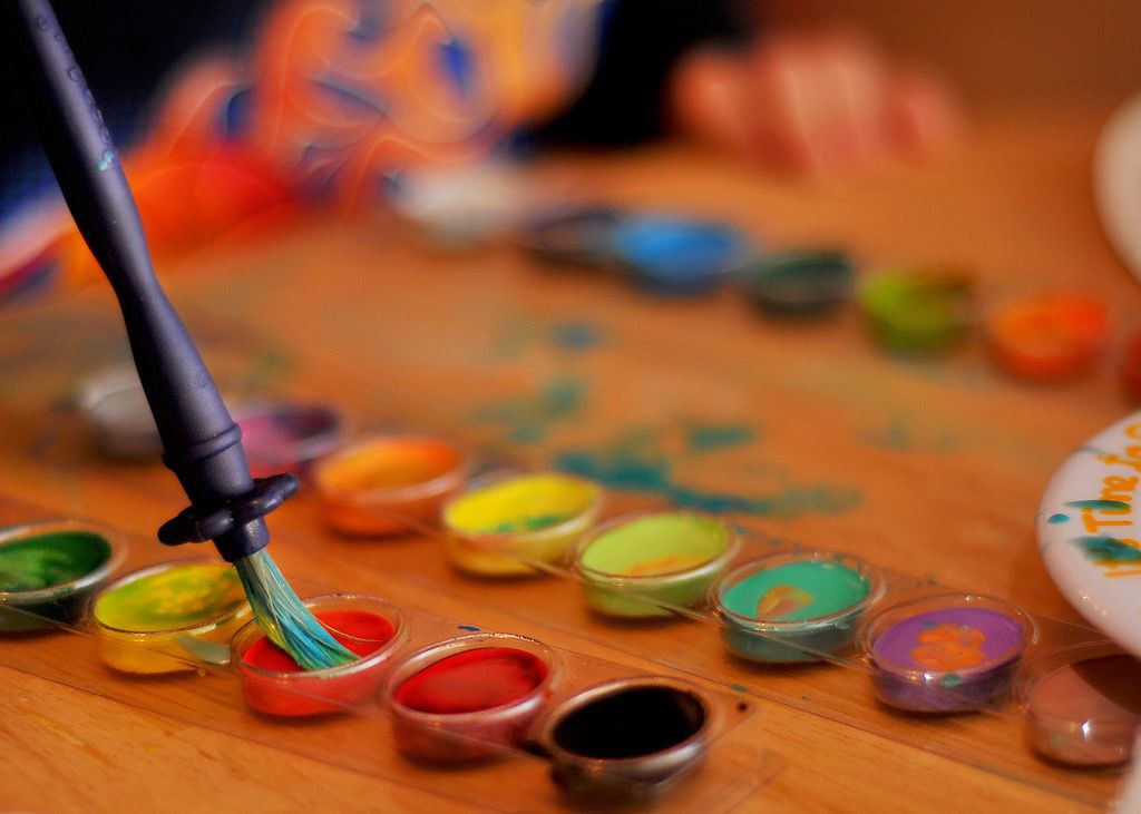 A pointed paintbrush being used with a set of watercolour pans.