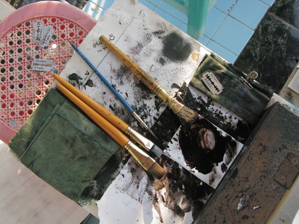 Artist's paintbrushes resting beside a palette and small painting in Sagaing, Myanmar.