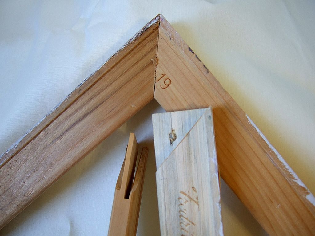 Two stretcher bars joined at a corner beside disassembled bars with slotted ends.