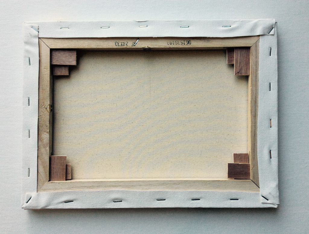Rear view of a modern stretched canvas showing woven fabric folded and stapled around wooden bars.