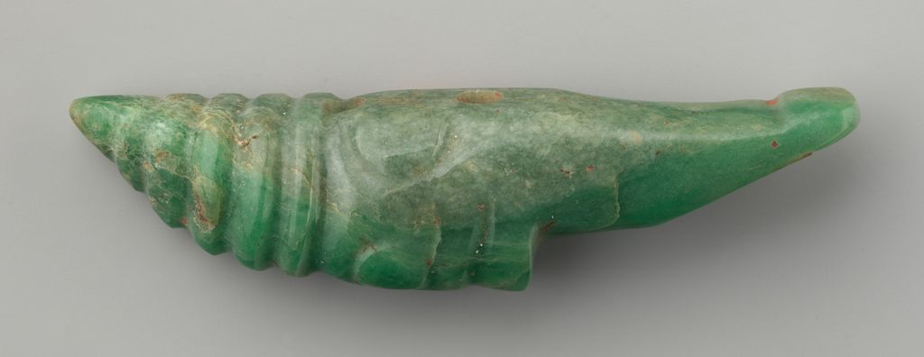 A long green jadeite ornament shaped as a hand retains scattered red cinnabar traces and drilled holes.