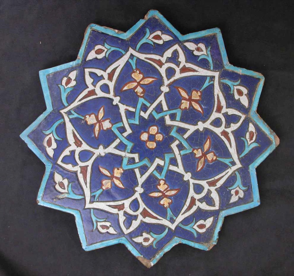 A complete Iranian tile has a twelve-pointed star profile around painted calligraphic and plant-like areas.