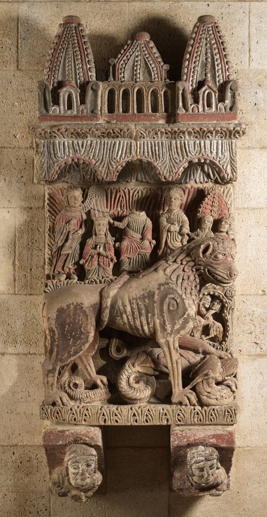 A carved medieval lion tramples a serpentine dragon beneath small sacred figures.