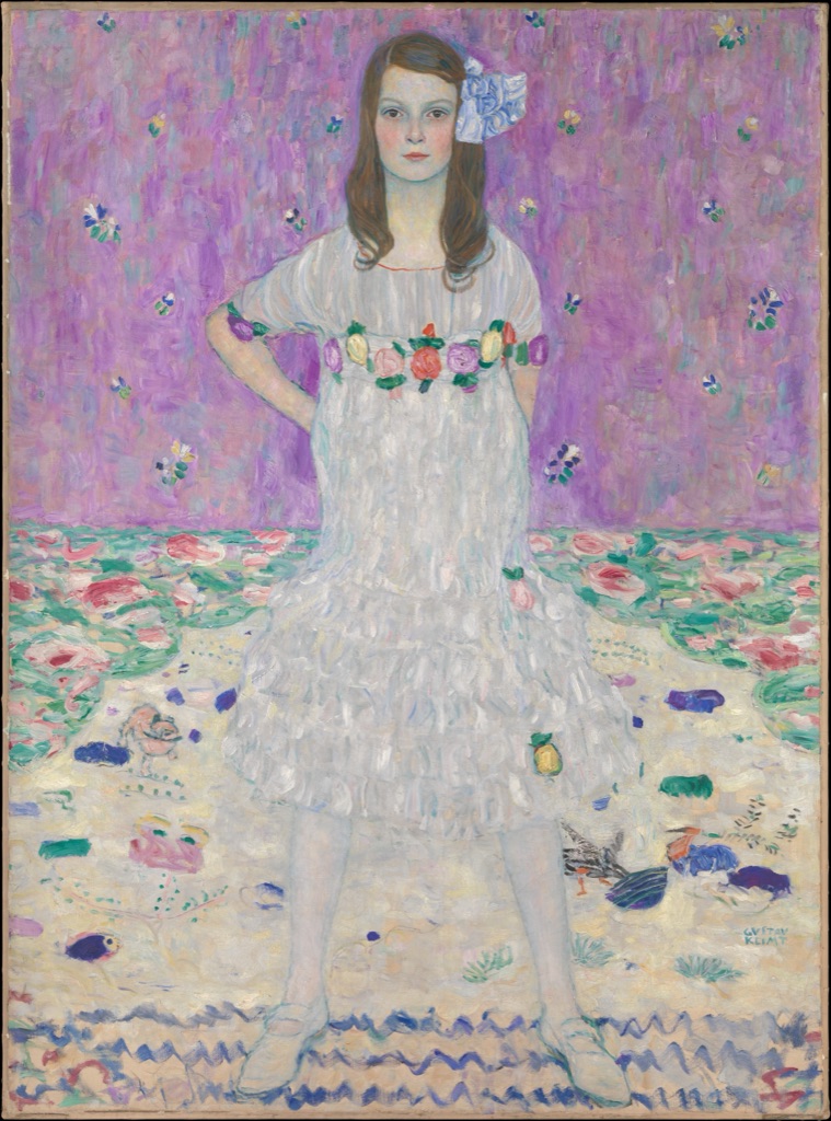 Klimt's Mäda Primavesi stands in a white dress amid scattered flowers, painted bands and repeated coloured shapes on a pale ground.
