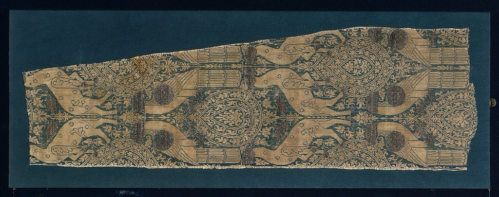 A long Italian silk fragment repeats paired gold birds and animals around oval plant motifs on a dark teal ground.
