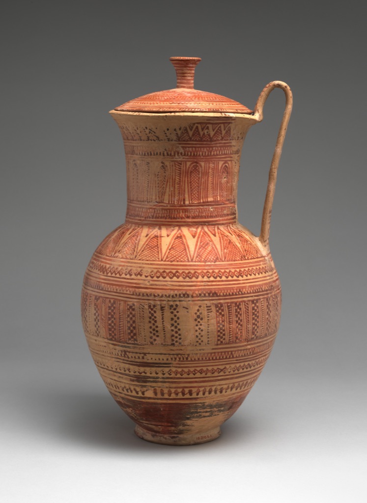 A tall terracotta pitcher and lid are wrapped in narrow red-brown geometric bands around the neck, shoulder and rounded body.